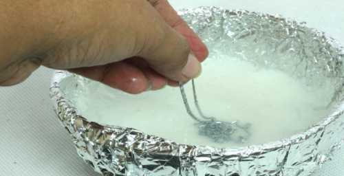 После закипания воды помещают в емкость небольшой кусок обычной пищевой фольги и опускают серебряное изделие